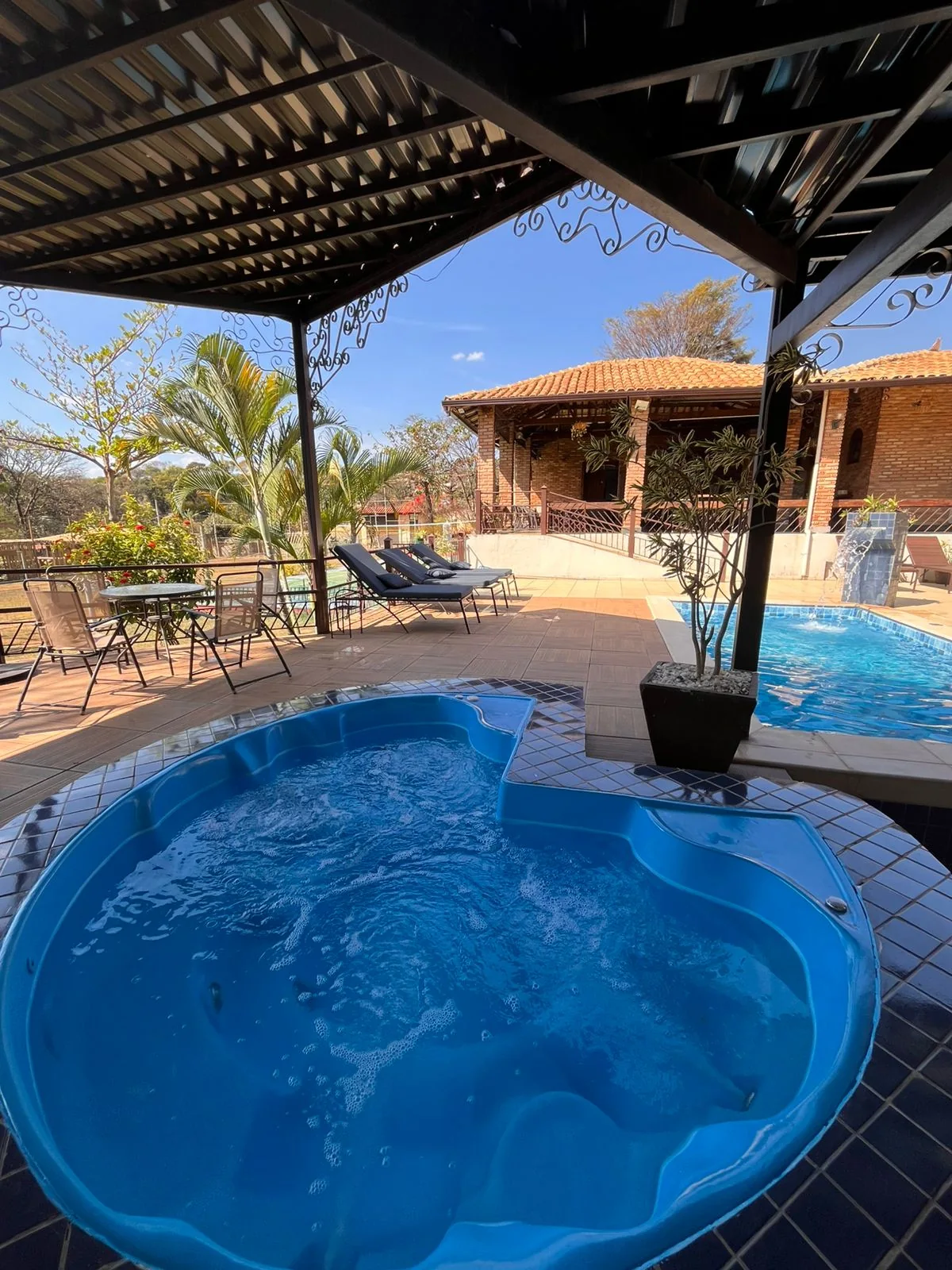 Jacuzzi aquecida com área da piscina e casa ao fundo
