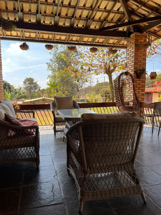 Área externa de convivência com poltronas, balanço suspenso e vista para o jardim