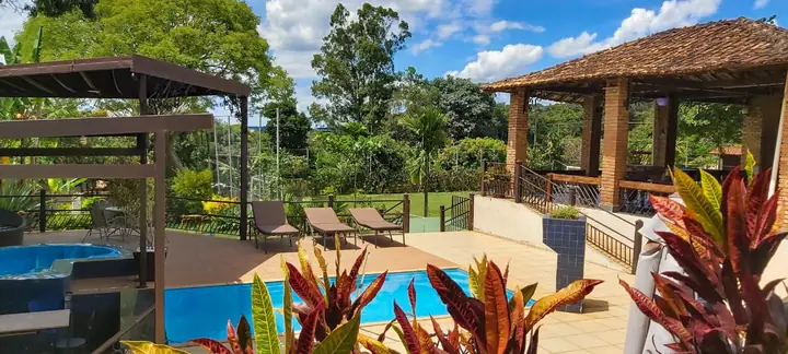 Vista da área de lazer com piscina, jardim e varanda do Pouso da Águia