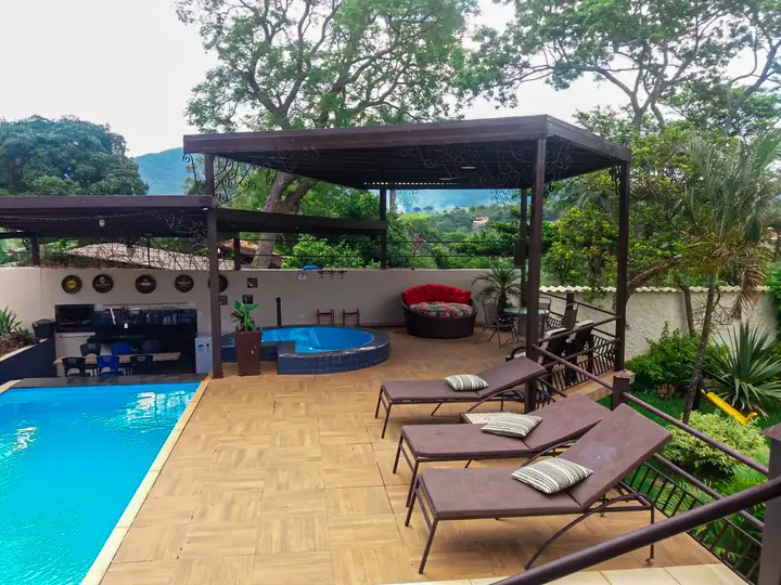 Piscina com espreguiçadeiras e área verde ao redor
