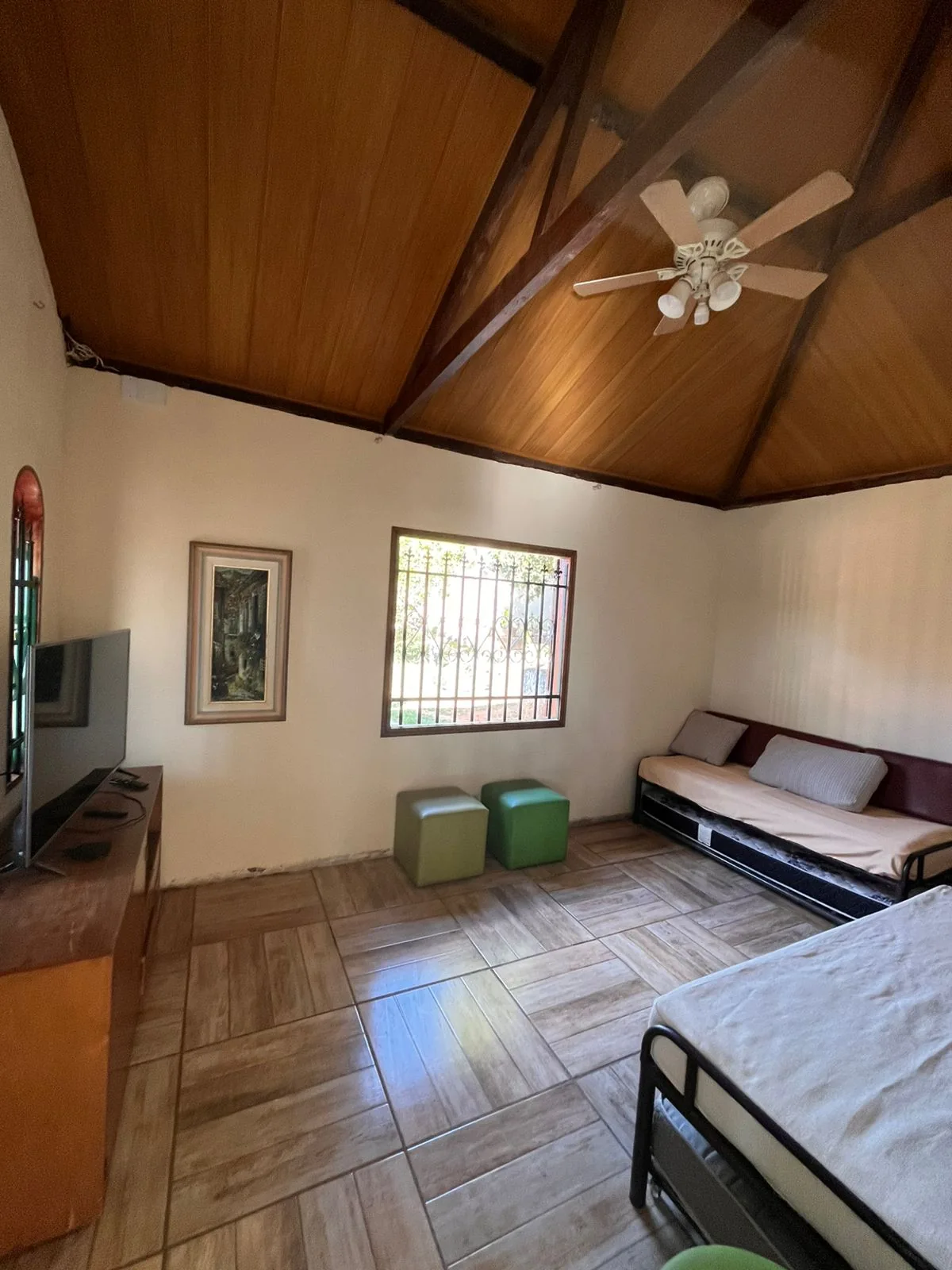 Sala de televisão com cama de casal e camas de solteiro